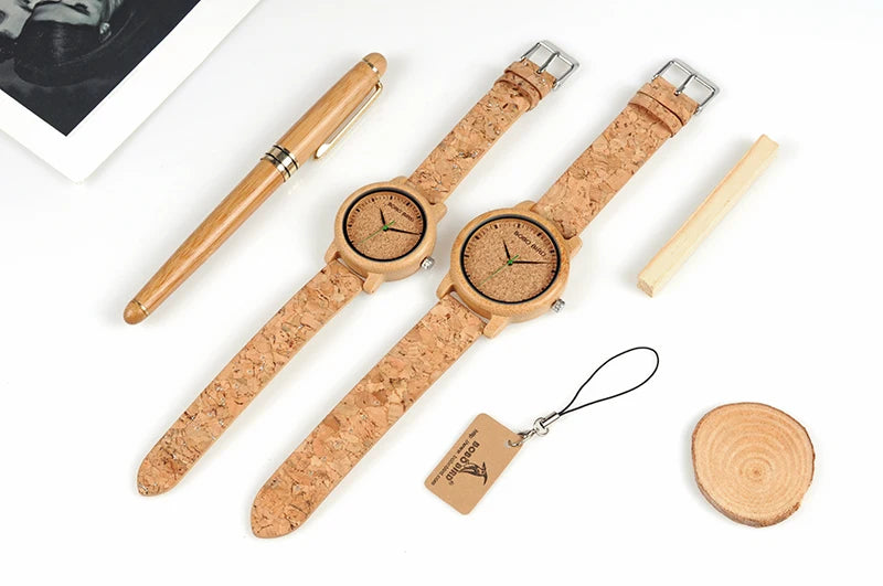 Two wooden watches with cork straps, a pen, and a keychain on a white background.