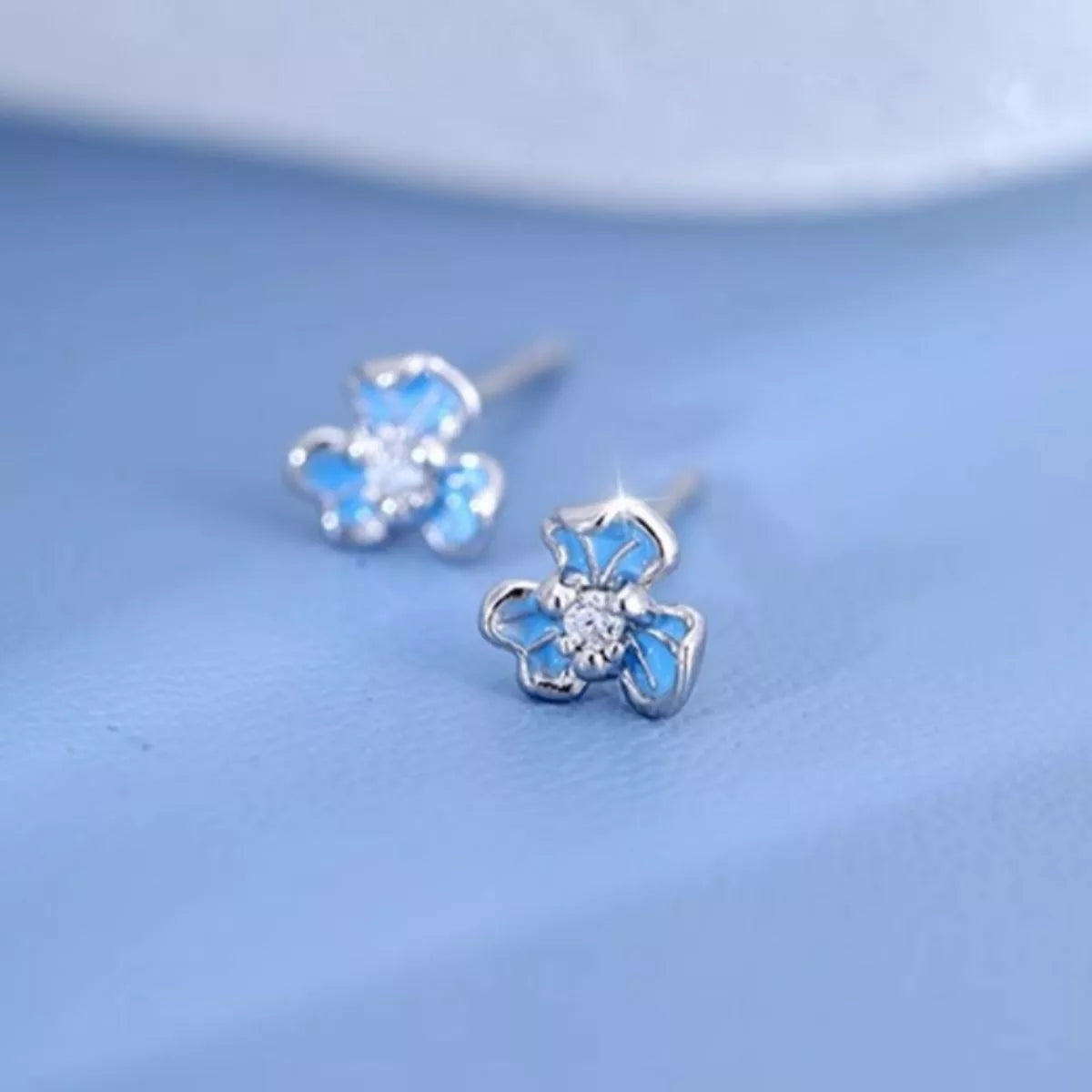 Butterfly-shaped earrings with blue accents on a light blue background