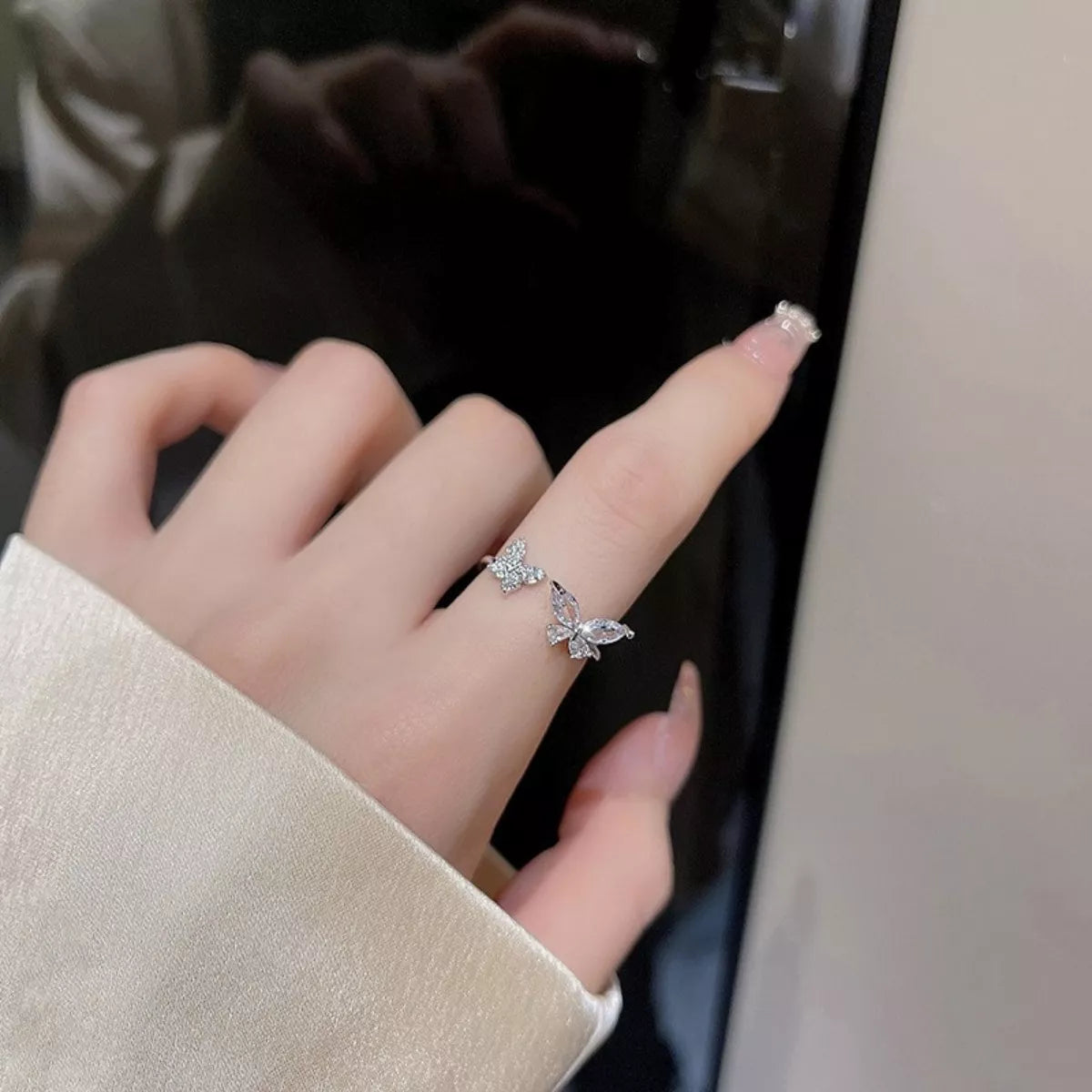 Hand wearing a butterfly-shaped silver ring with a blurred background