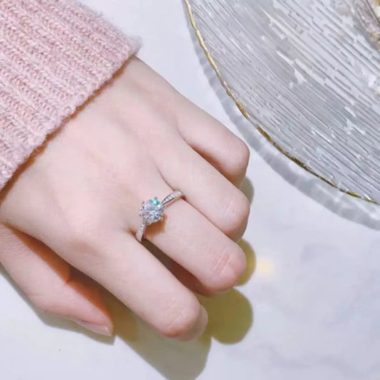 Hand wearing a silver ring with a gemstone on a light background