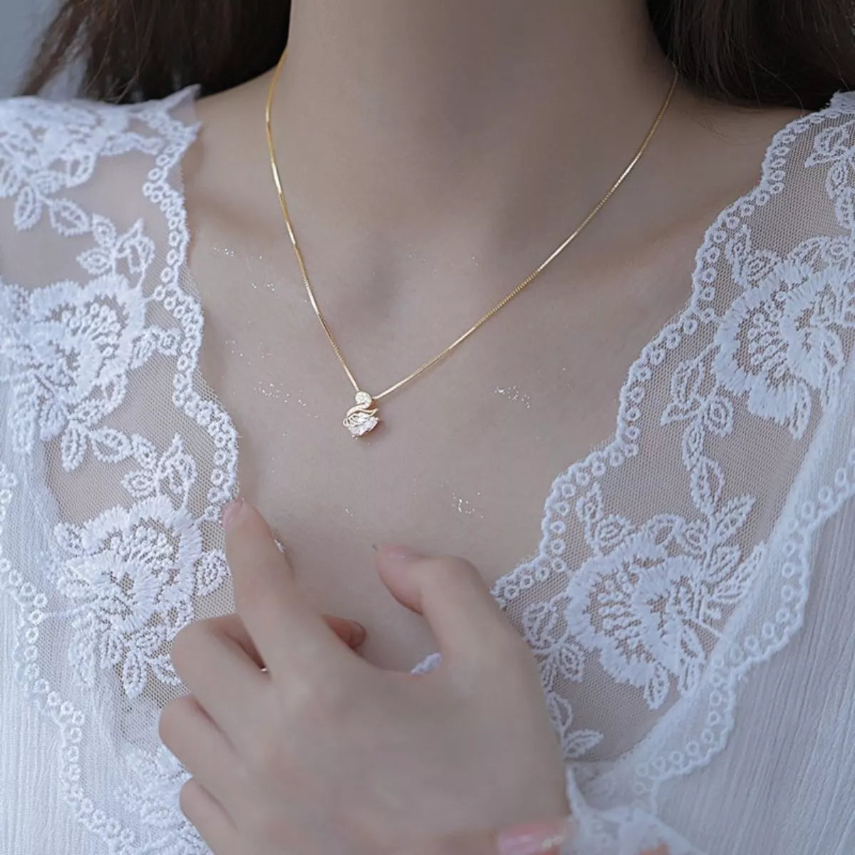 Gold necklace on a person wearing a white lace garment