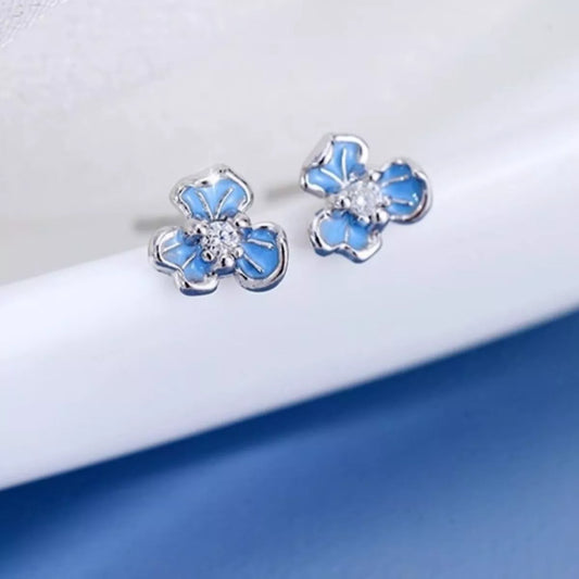 Blue flower-shaped earrings on a white and blue gradient background