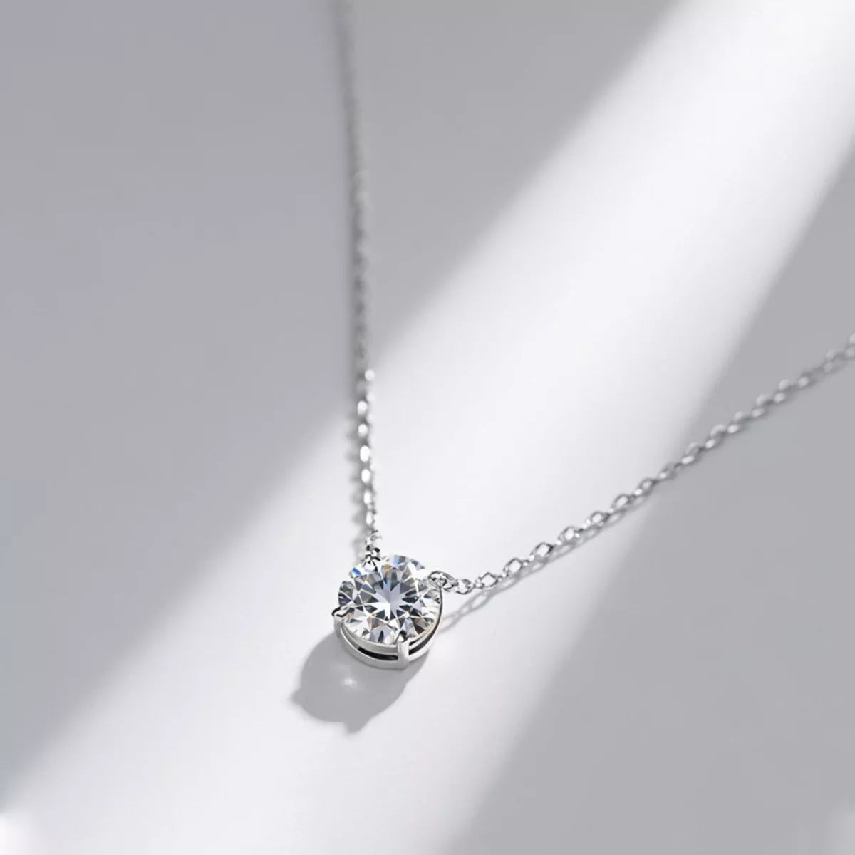Silver necklace with a round diamond pendant on a light gray background