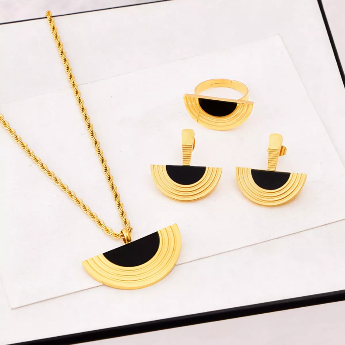 Gold and black jewelry set on a white surface
