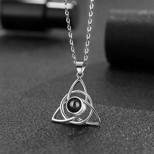 Silver necklace with a black pendant on a textured surface