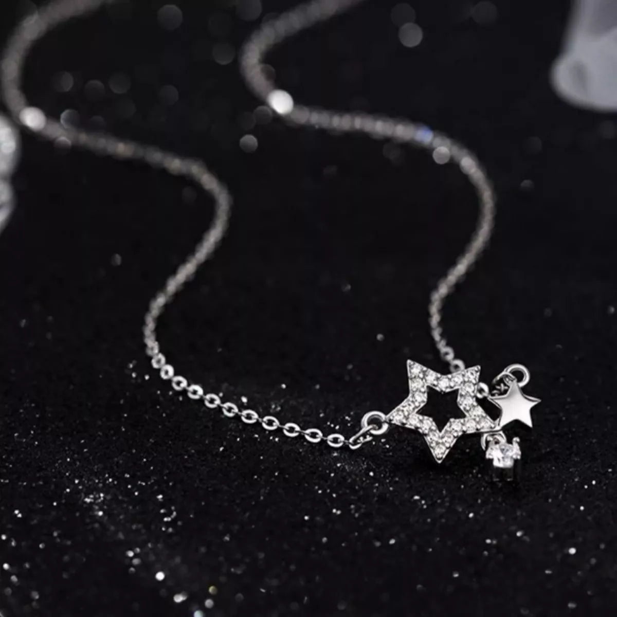 Silver necklace with star-shaped pendant on a black background