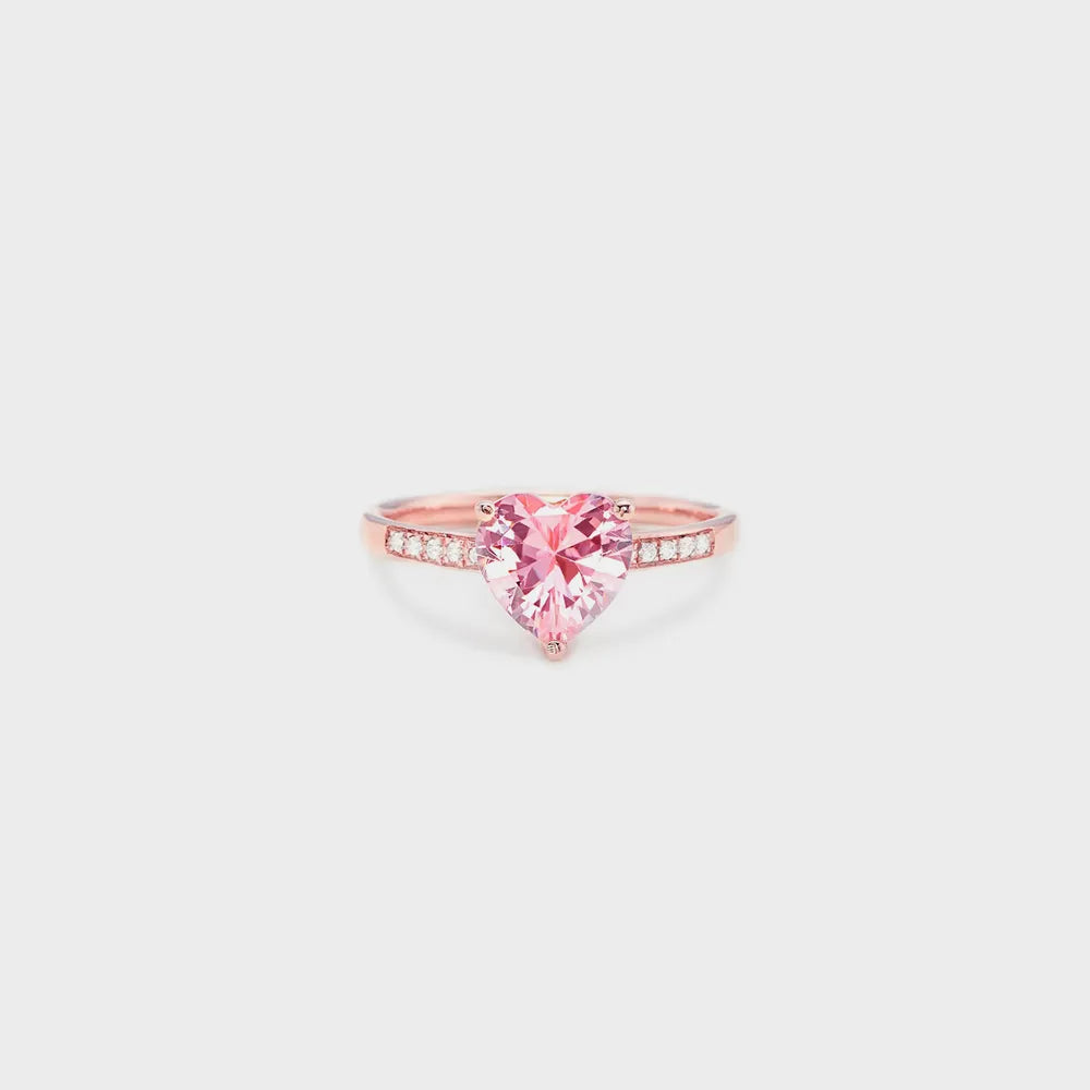 Rose gold ring with a pink heart-shaped gemstone on a light gray background