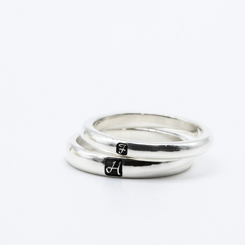 Two silver rings with engraved initials on a white background