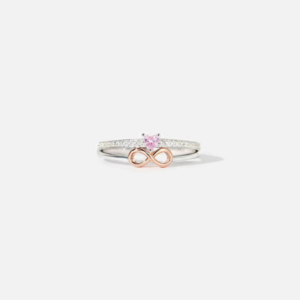Ring with infinity symbol and pink gemstone on a white background
