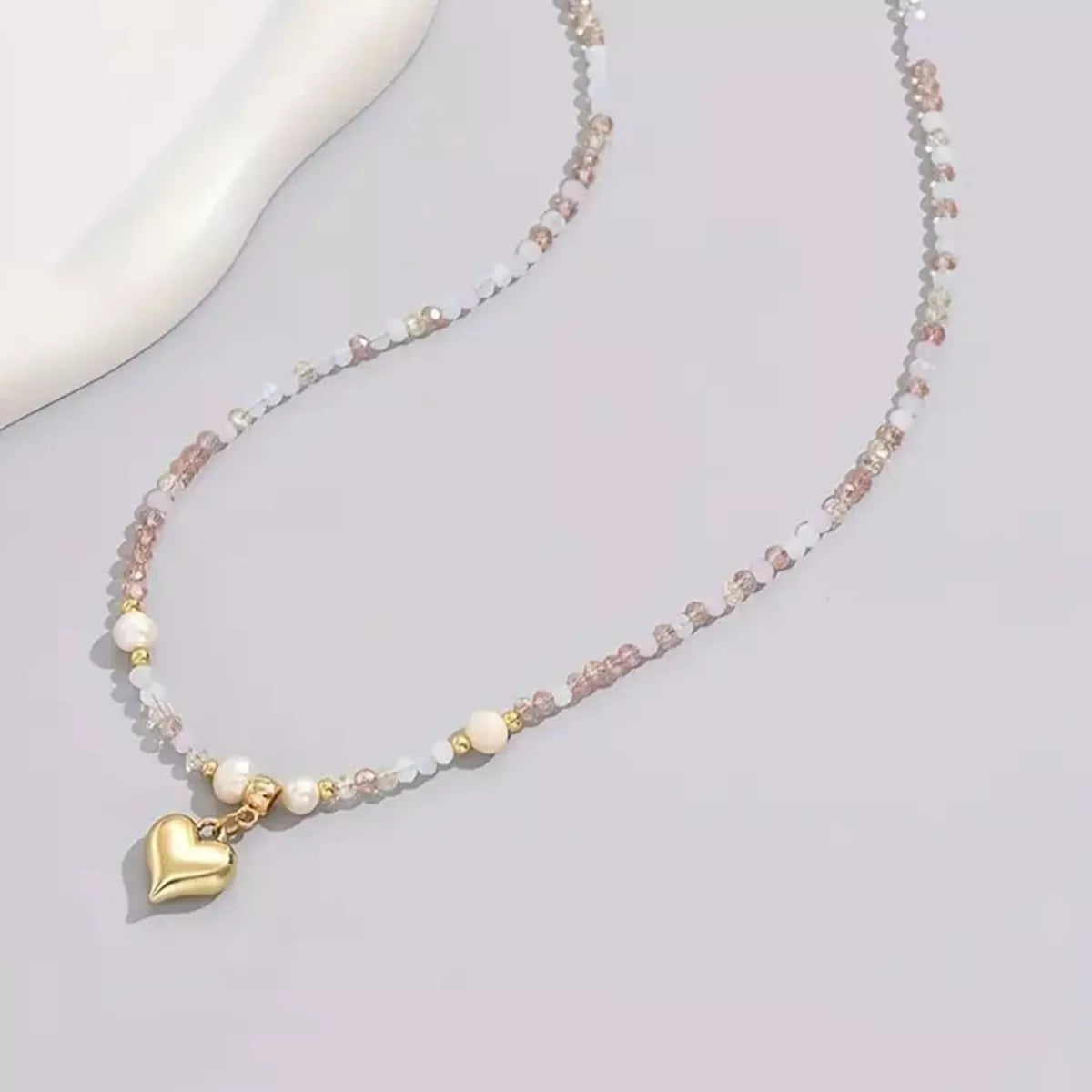 Necklace with heart charm on a light gray background