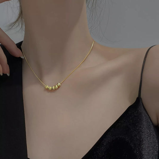 Gold necklace being worn on a person's neck with a neutral background