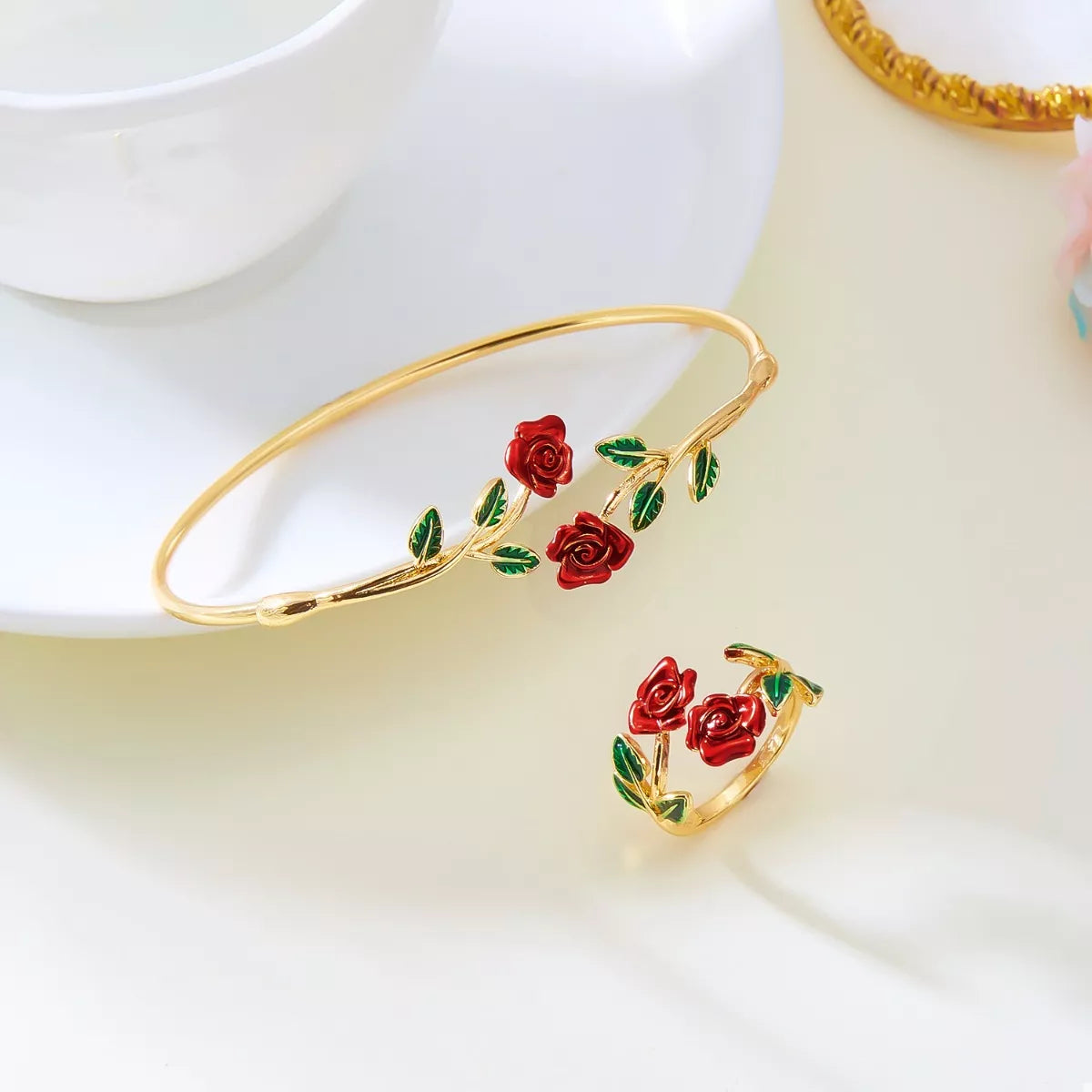 Gold bracelet with red rose designs on a white surface