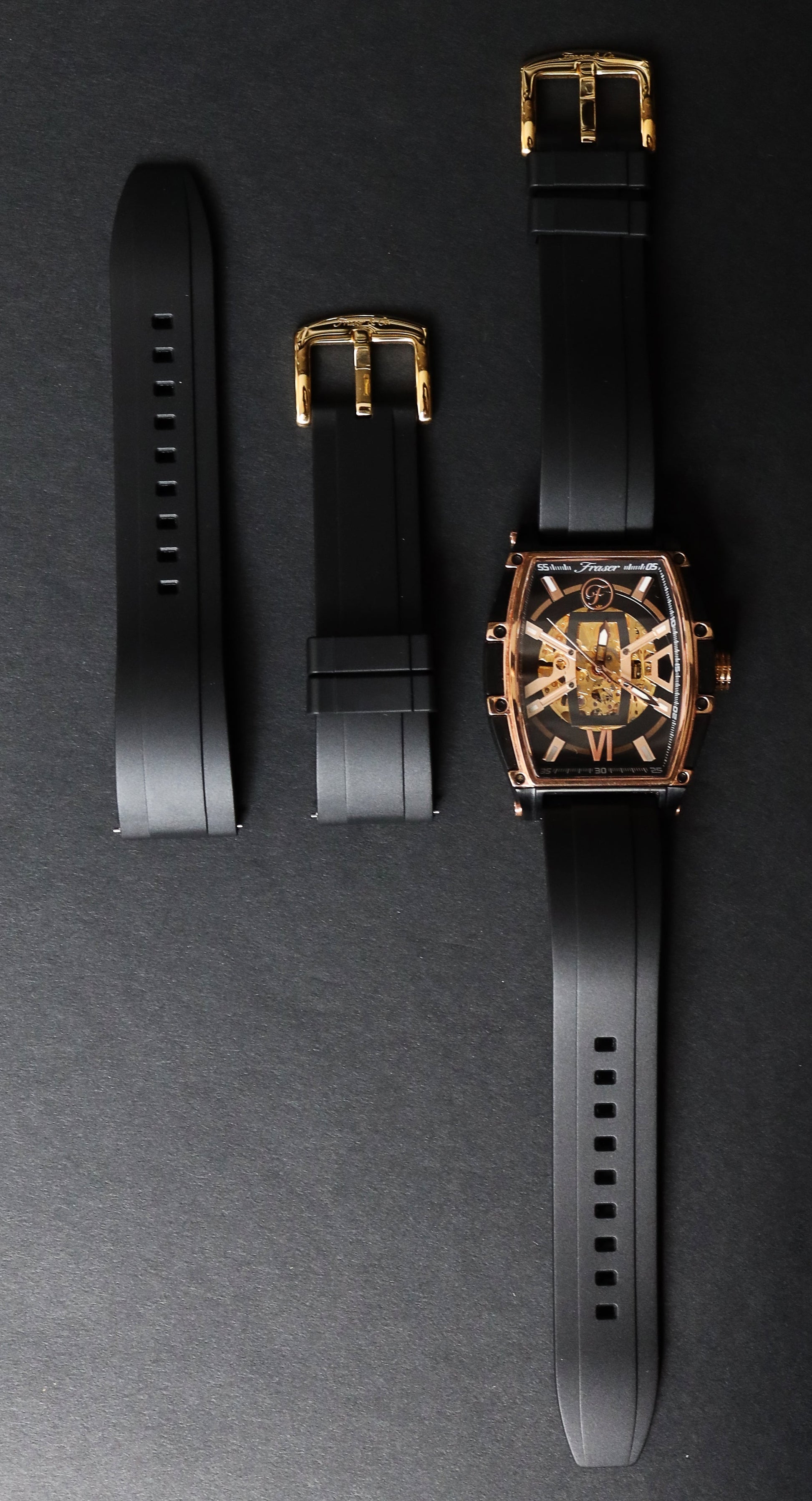 Luxury watch with black strap and gold accents on a dark gray background