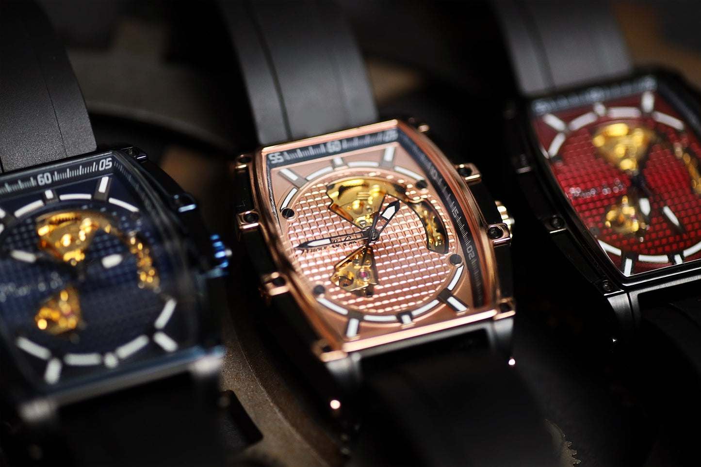 Three luxury watches with intricate designs on a dark background