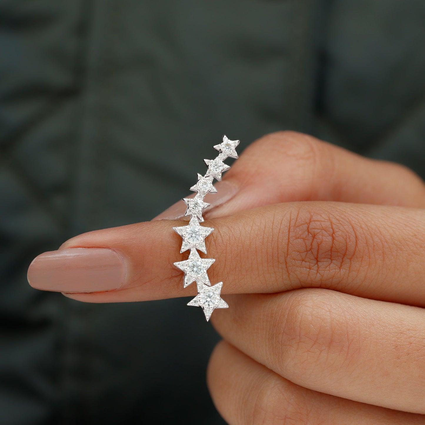 Star-shaped earrings held between fingers against a blurred background
