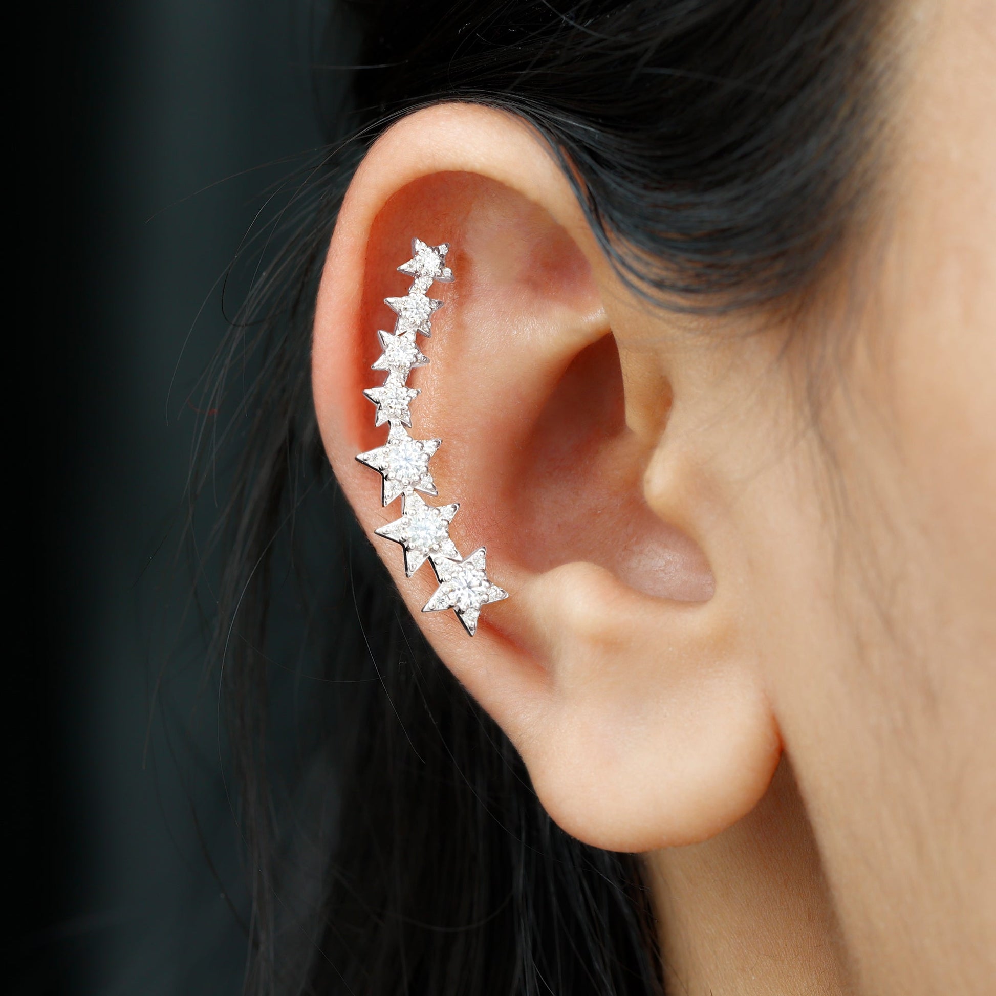Star-shaped earring worn on an ear with a dark background