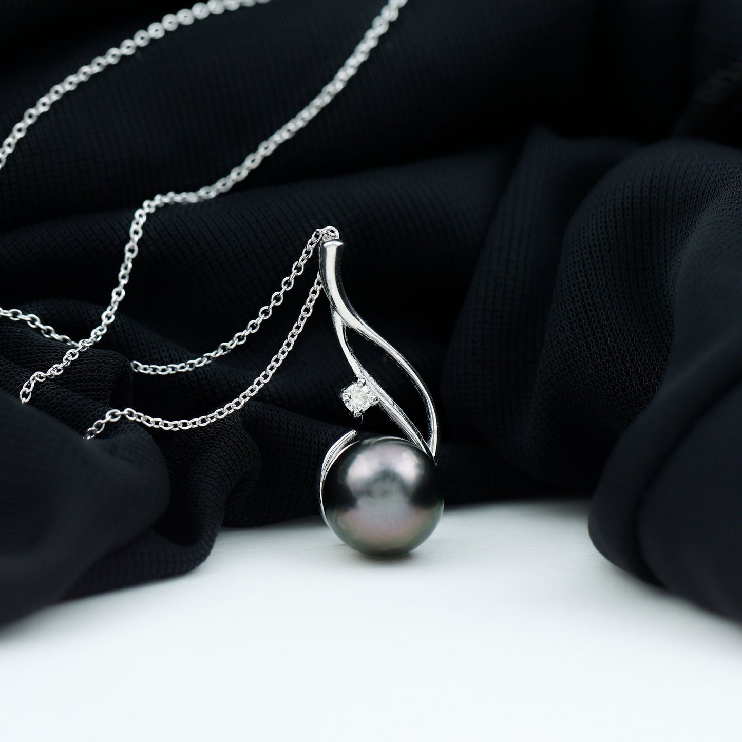 Pearl necklace with silver chain on a black fabric background