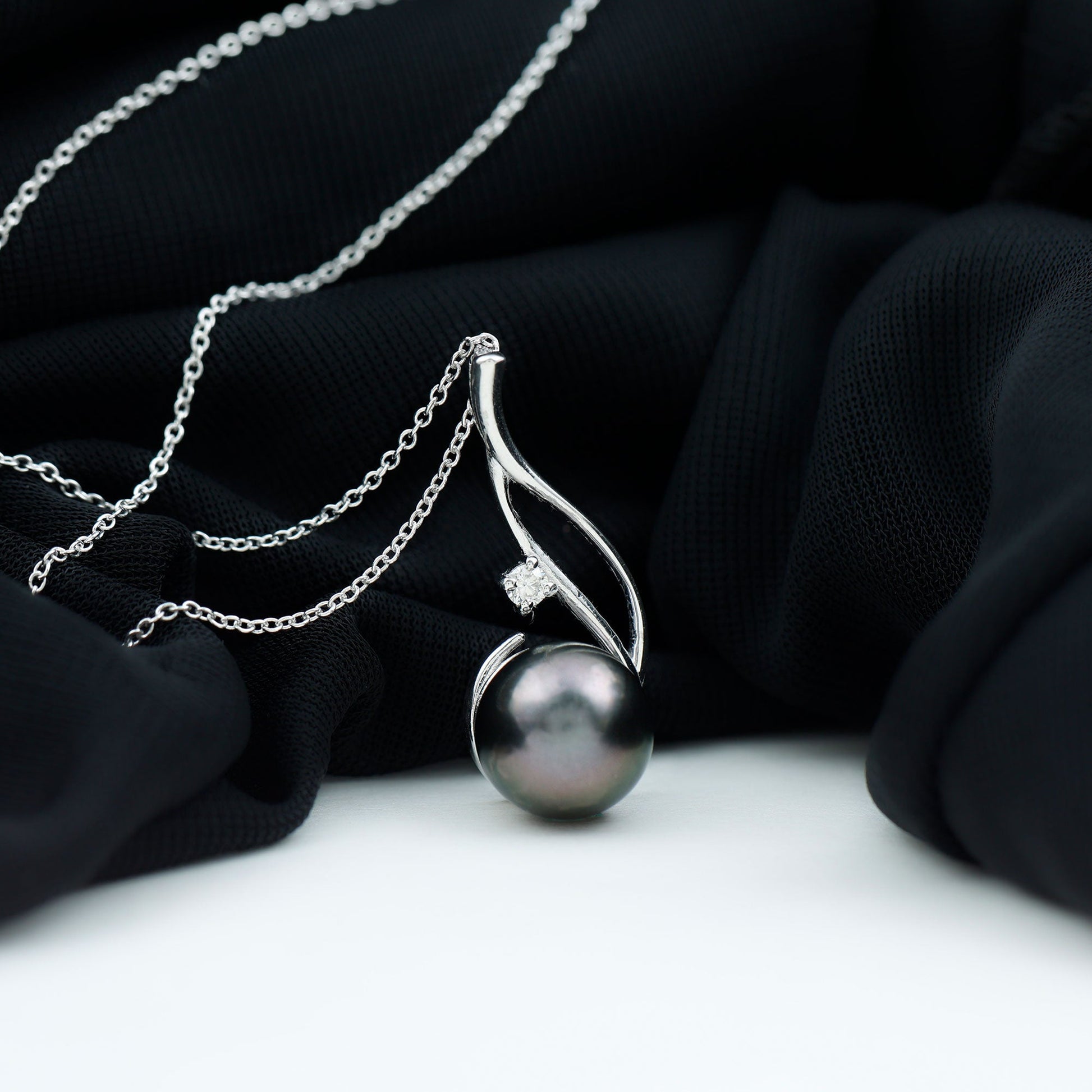 Pearl necklace with silver chain on a black fabric background