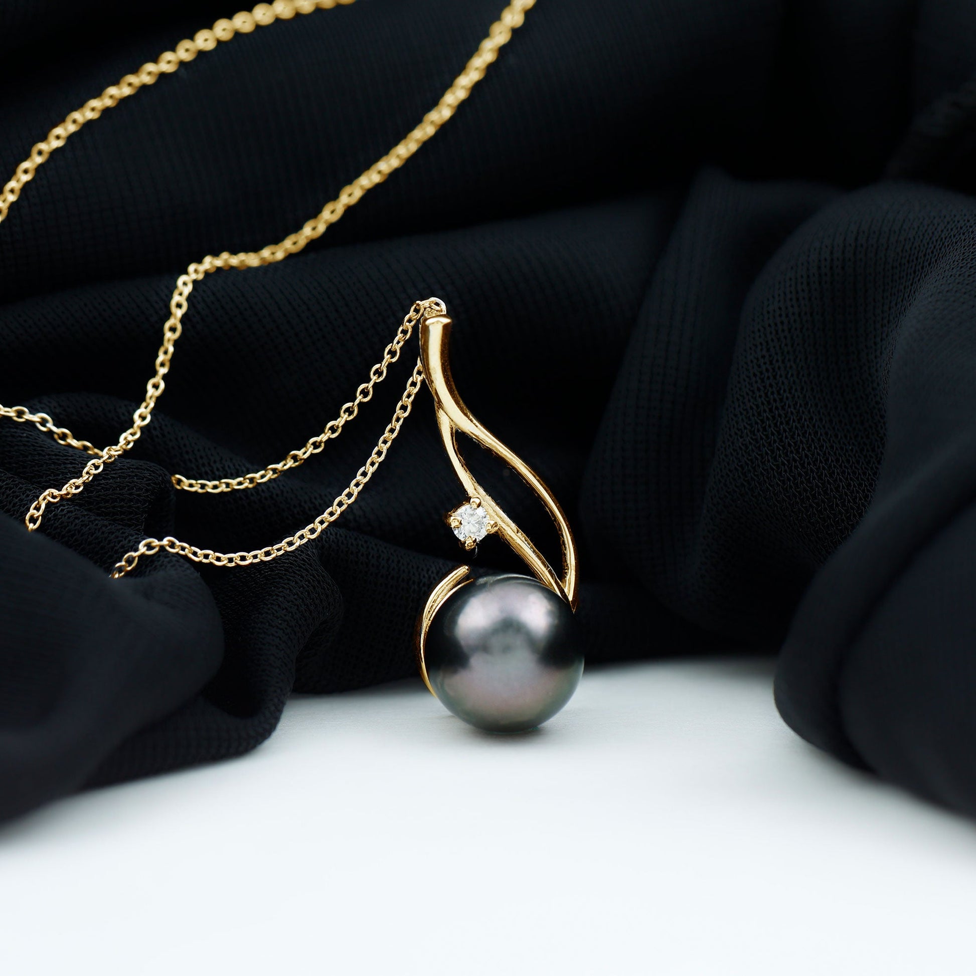 Pearl necklace with gold chain on a black fabric background
