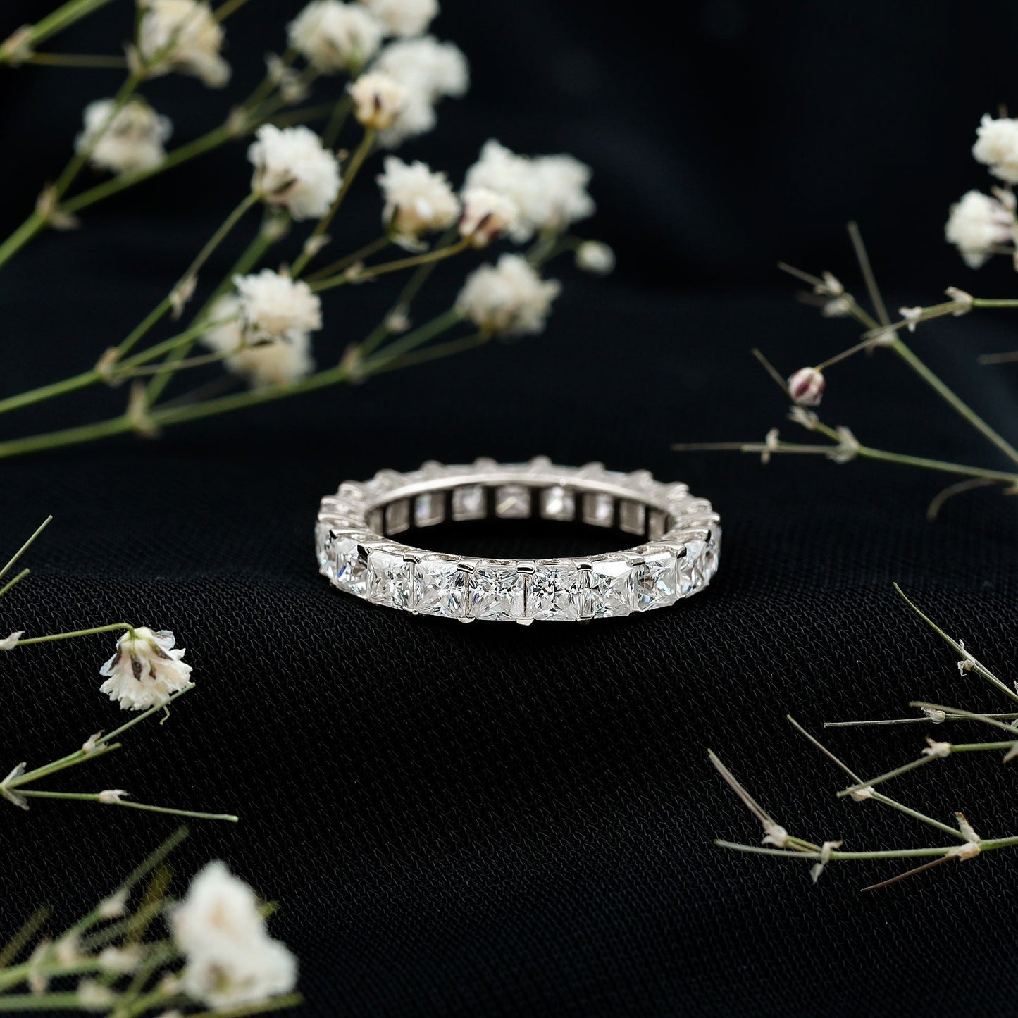 Gold ring with diamonds on a black background with white flowers