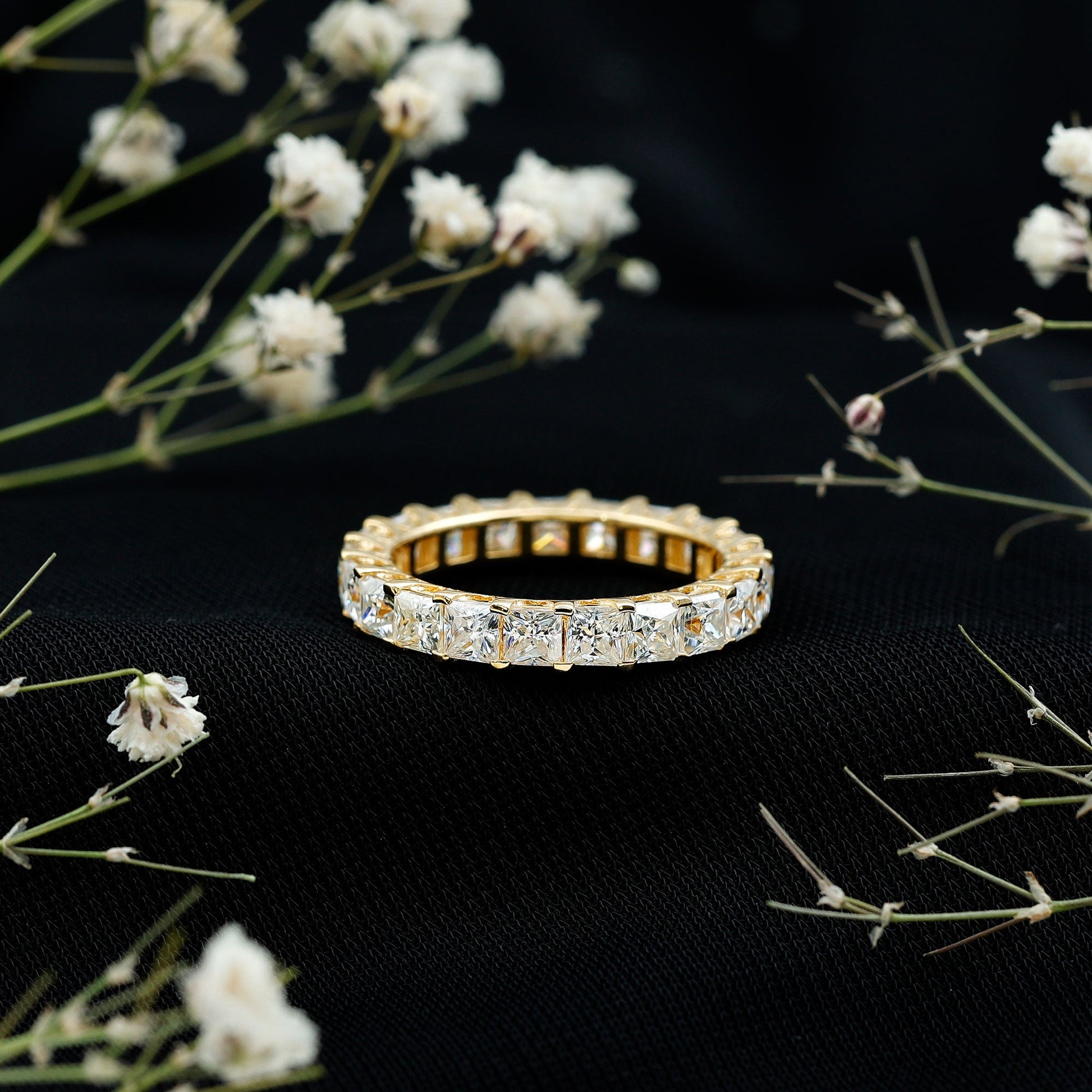 Gold ring with diamonds on a black background with white flowers