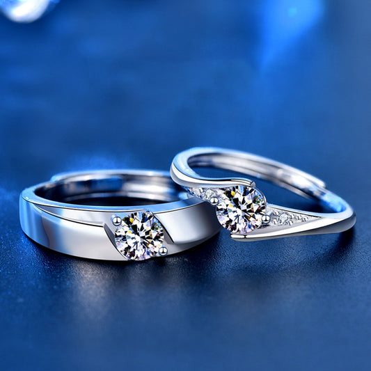 Honey Moon 925 sterling silver couple's matching adjustable rings with round cubic zirconia center stones on a dark blue reflective surface