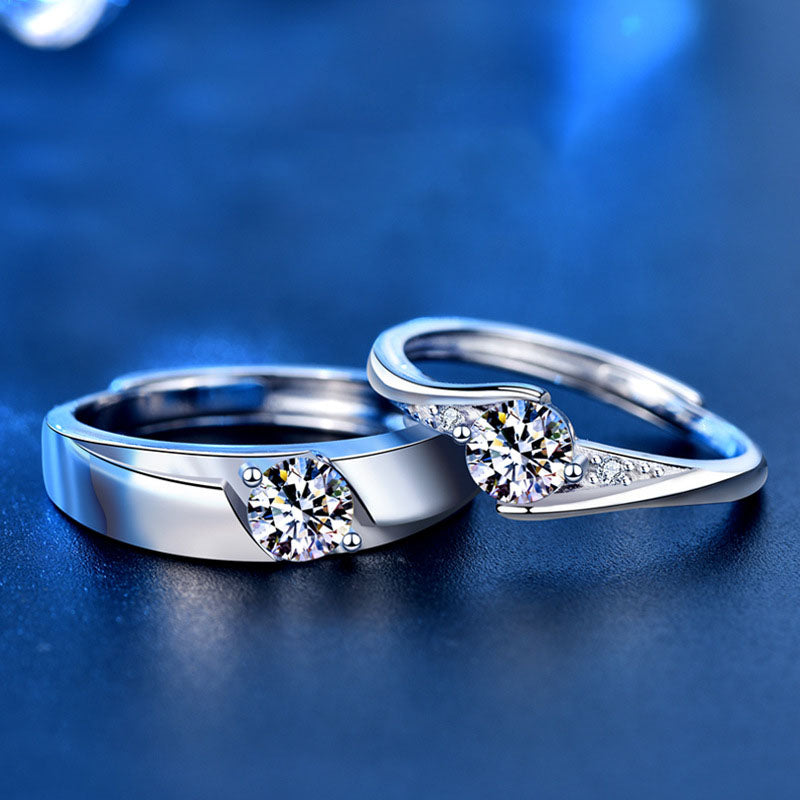Honey Moon 925 sterling silver couple's matching adjustable rings with round cubic zirconia center stones on a dark blue reflective surface