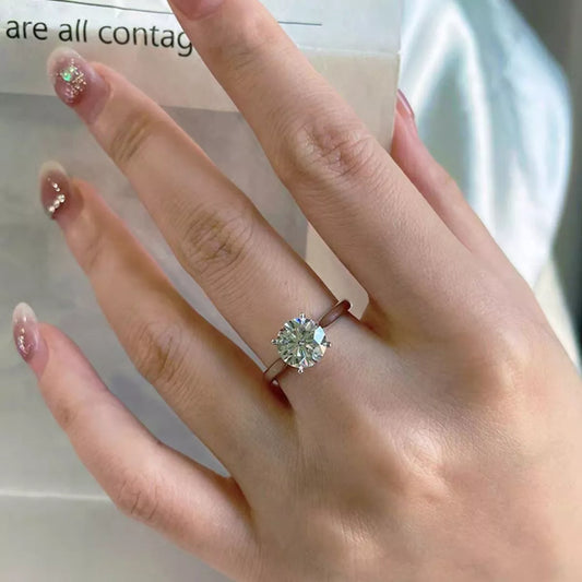 Hand wearing a diamond ring with blurred text in the background