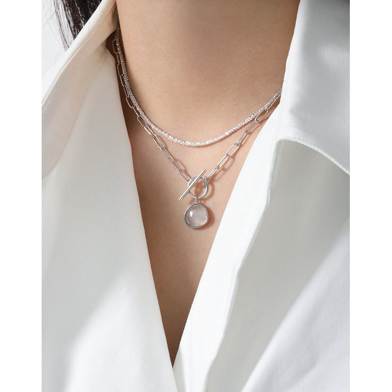 Necklace with a pendant worn by a person in a white shirt