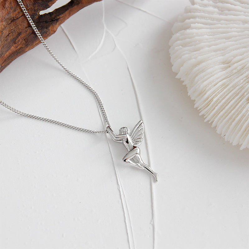 Silver angel pendant necklace on a white surface with natural elements.