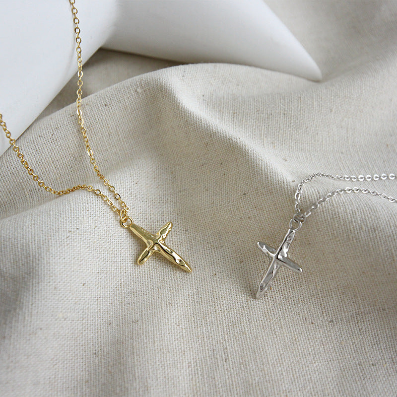 Gold and silver cross necklaces on a textured fabric background