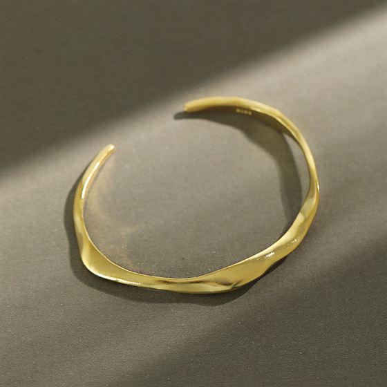 Gold bracelet on a gray surface