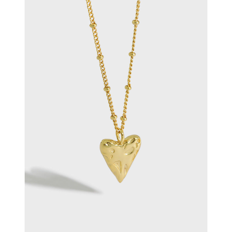 Gold heart-shaped pendant necklace on a light gray background