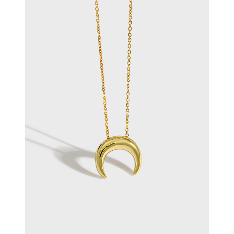 Gold crescent moon necklace on a light gray background