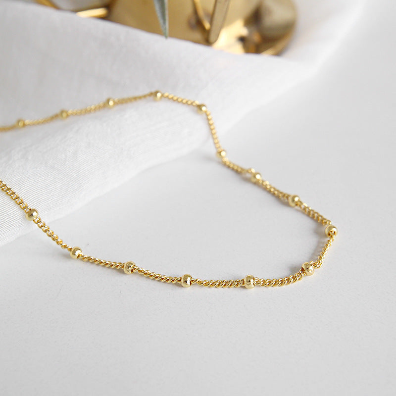 Gold chain necklace on a white surface