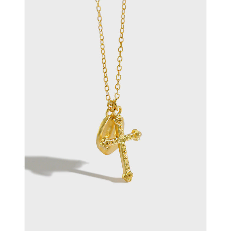 Gold necklace with a cross pendant on a light gray background