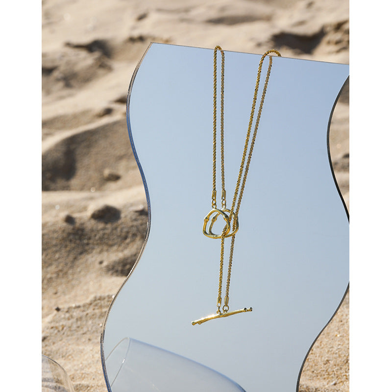 Gold necklace on a mannequin against a desert landscape background
