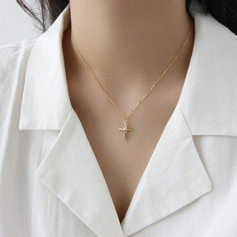 Gold necklace with a cross pendant on a white shirt