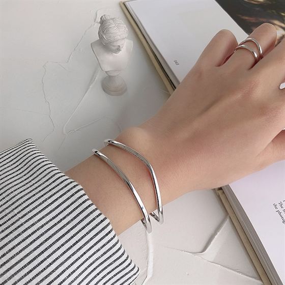 Silver bracelet on a wrist with a neutral background
