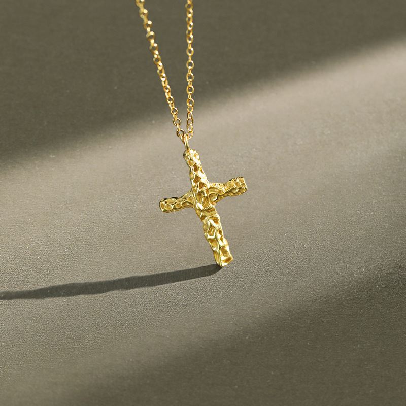Gold cross necklace on a dark surface