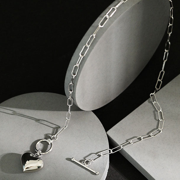 Silver chain necklace with a heart-shaped pendant on a black and gray background