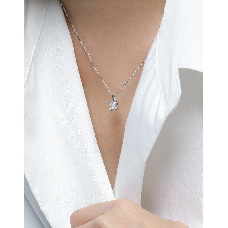 Silver necklace with a diamond pendant worn by a person in a white shirt.