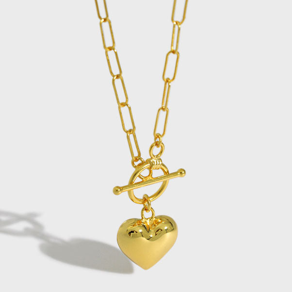 Gold necklace with a heart pendant on a light gray background