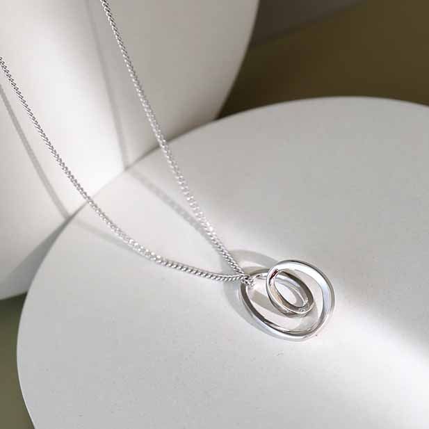 Silver necklace with a circular pendant on a white surface
