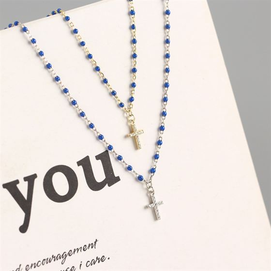 Necklace with blue beads and crosses on a card with the word 'you'.