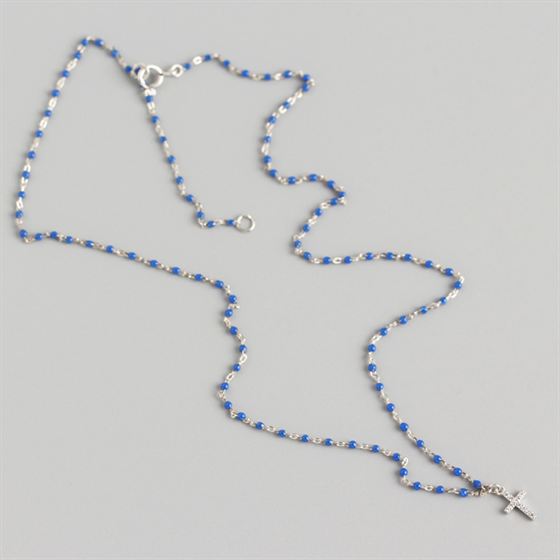 Necklace with blue beads and a silver cross on a gray background