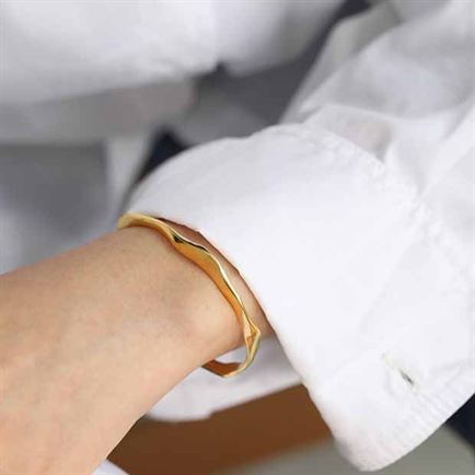 Gold bracelet on a wrist with a blurred background