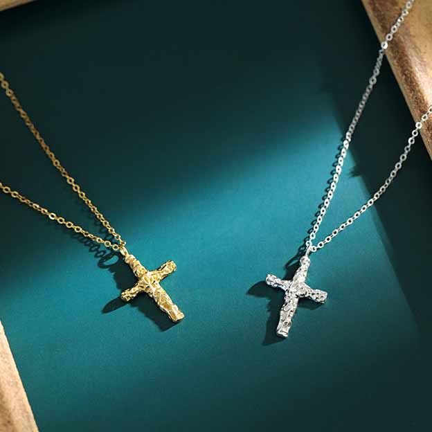 Gold and silver cross necklaces on a teal surface