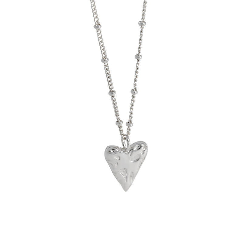 Silver heart-shaped pendant on a chain against a white background