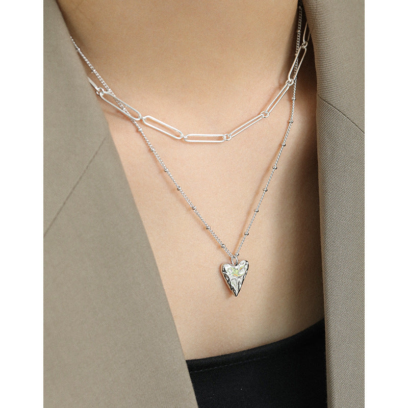 Necklace with a heart-shaped pendant worn by a person against a neutral background